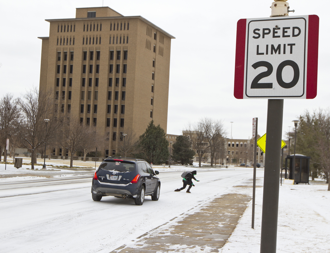 A student slips on ice in front of a car while crossing Flint Avenue on Feb. 6, 2014.